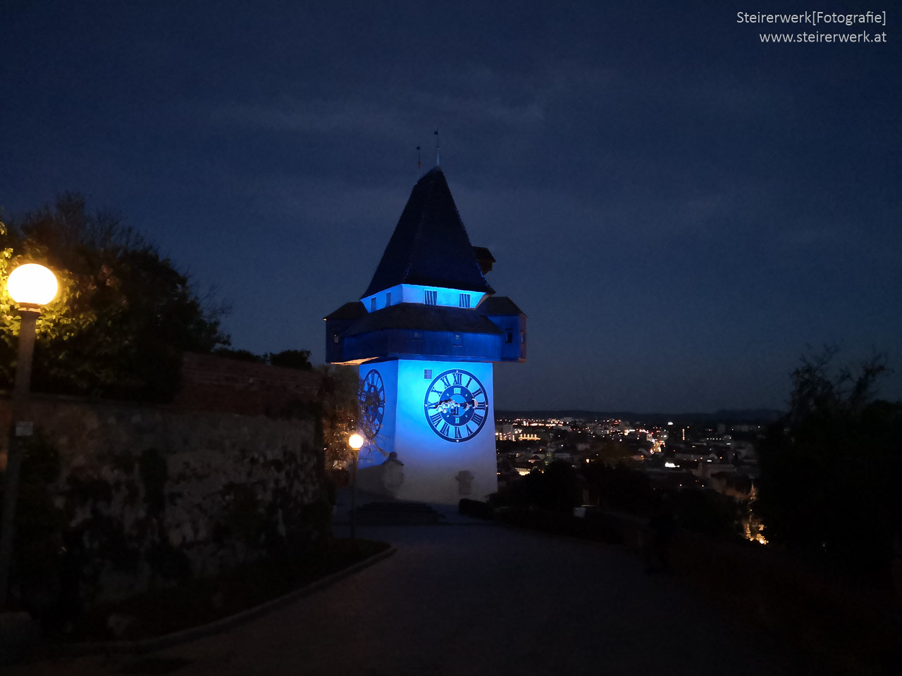Uhrturm gelb blau beleuchtet